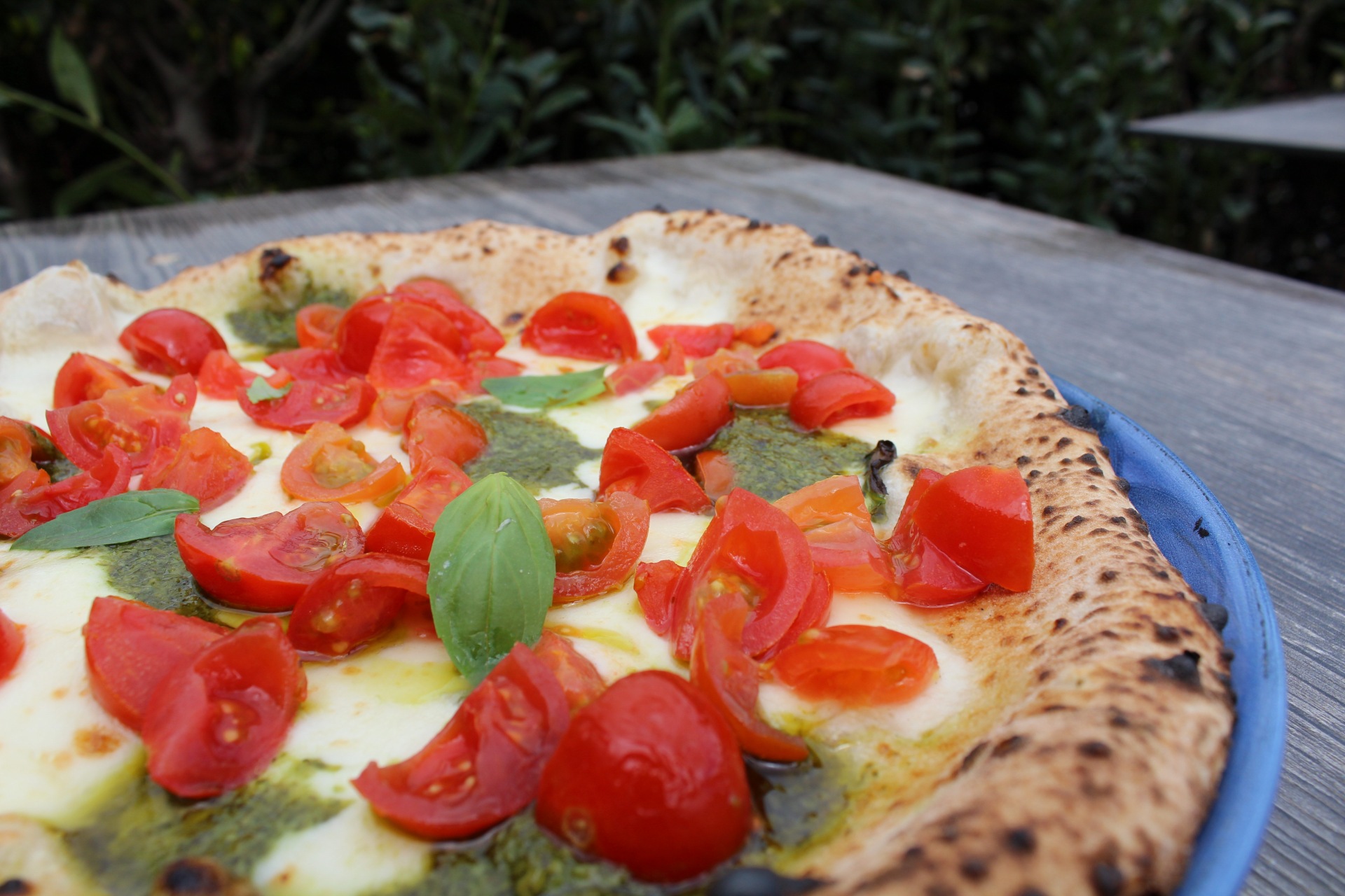 Pizza con pesto e pomodorini freschi servita all'aperto a Siena