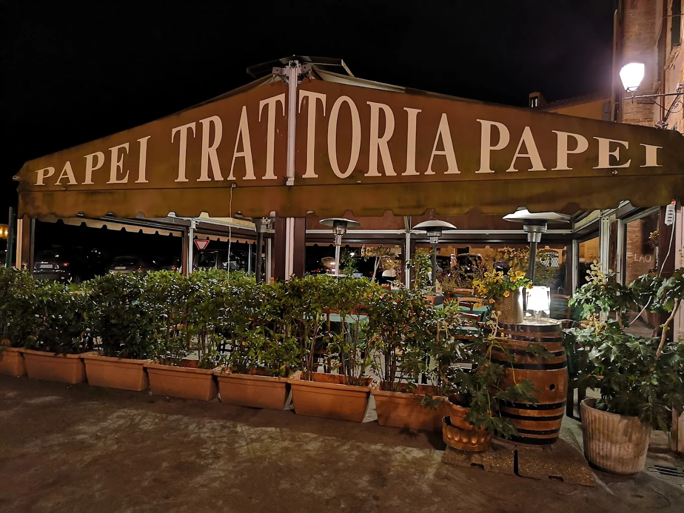 Esterno dell'Antica Trattoria Papei in Piazza del Mercato a Siena, con tende e insegna illuminata di sera